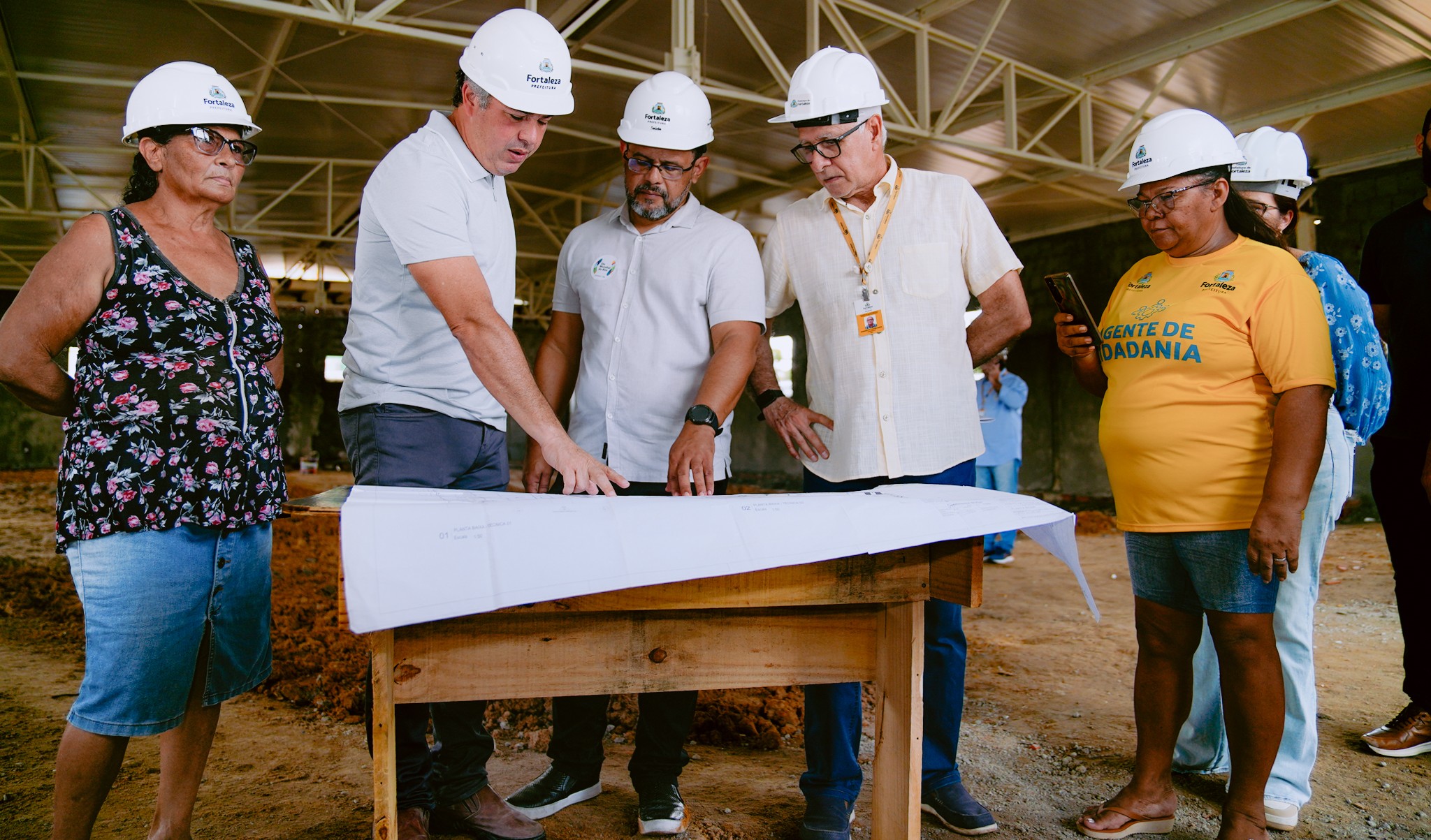 grupo de pessoas olha a planta de uma obra